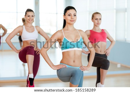 Aerobics class Three beautiful young women in sports clothing exercising together and smiling Aerobics class Three beautiful young women in sports clothing exercising together and smiling
