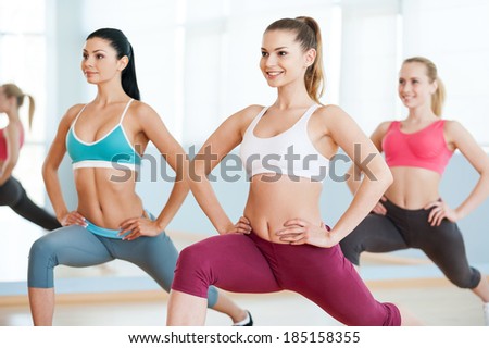 Girls on aerobics class. Three beautiful young women in sports clothing exercising together and smiling