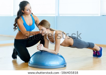 Woman doing push-ups. Beautiful young woman in sports clothing doing push-up with her personal instructor