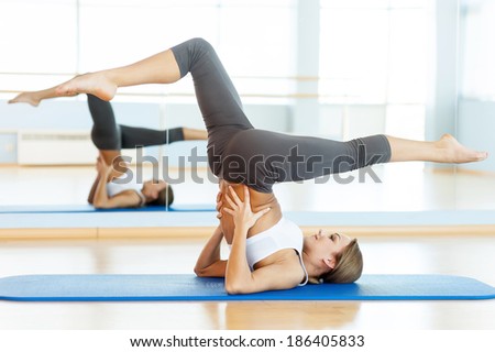 Woman training. Side view of beautiful young woman training on yoga mat