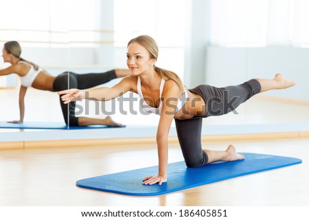 Sports training. Side view of beautiful young woman training on yoga mat