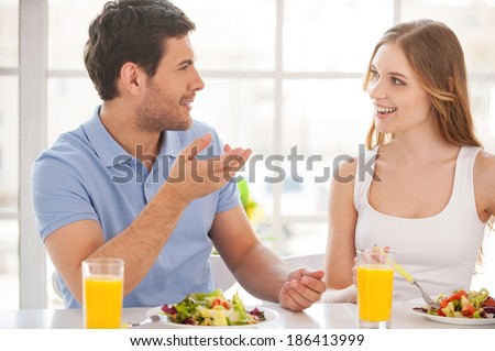 Couple having breakfast. Beautiful young couple sitting together at the breakfast table and talking
