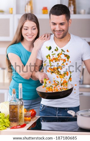 They love cooking together. Beautiful young couple cooking together in the kitchen