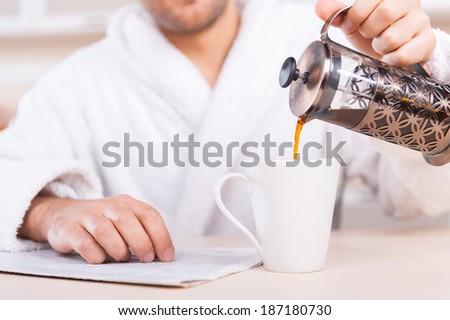 Pouring fresh coffee. Cropped image of man in bathrobe pouring coffee to the cup