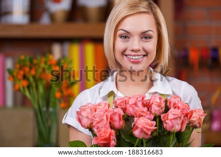Blond beauty with bunch of roses. Attractive young blond hair woman in apron holding bunch of roses and smiling
