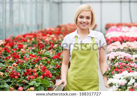 Women in flowers. Beautiful blond hair woman standing in flower bed and smiling