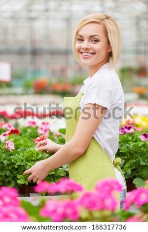 I love my job. Beautiful young woman in apron gardening and looking at camera