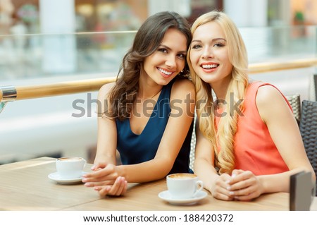 Two friends in cafe. Two young female friends sitting in cafe and looking at camera