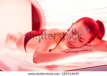 Sunbathing on tanning bed. Beautiful young woman lying on tanning bed and keeping eyes closed