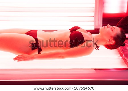 Sunbathing on tanning bed. Beautiful young woman lying on tanning bed and keeping eyes closed