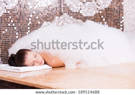 Soapy pleasure. Beautiful young woman relaxing in Turkish bath with foam