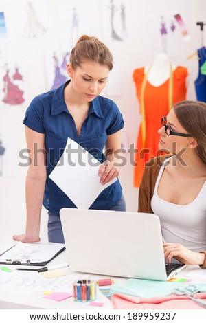 Working out everyday issues. Two beautiful female designers discussing something while looking at the laptop