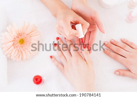 Manicurist in action. Top view of manicurist doing red manicure