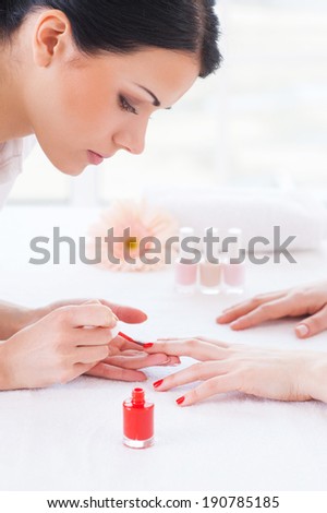 Making red manicure. Close-up of beautician doing red  manicure to female customer