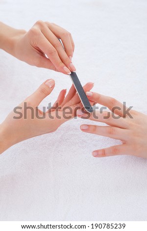 Nail care. Close-up of beautician polishing nails of female customer