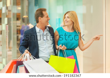 Look at this dress! Beautiful mature couple shopping together while woman pointing away and smiling