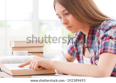 Studying hard. Side view of confident teenage girl studying while sitting at the desk