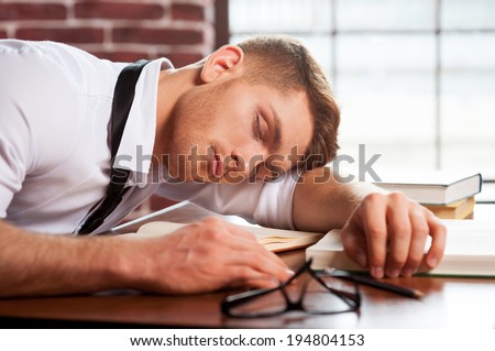Sleeping author. Handsome young man in shirt and tie sleeping while sitting at the desk