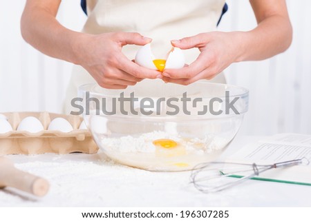 Cracking an egg to a bowl. Close-up of woman cracking egg for pastry