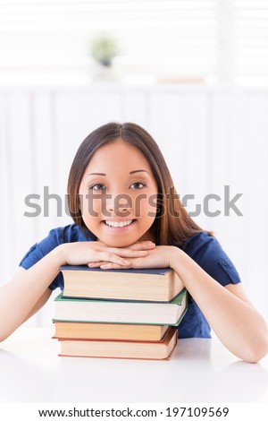 Beautiful bookworm. Beautiful young Asian woman reading a book while sitting at the table