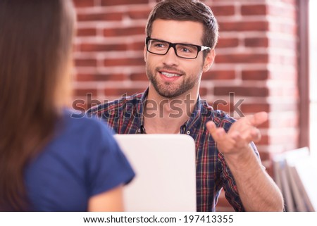 Business talk. Two business people in casual wear talking and smiling while sitting face to face at the table