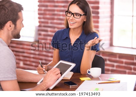 Discussing business. Two cheerful business people in casual wear talking and gesturing while sitting at the table