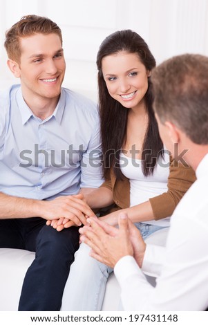 Listening to an expert advice. Happy young couple discussing financial matter with financial consultant