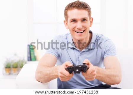 Man playing video game. Happy young man using joystick while playing video game at home