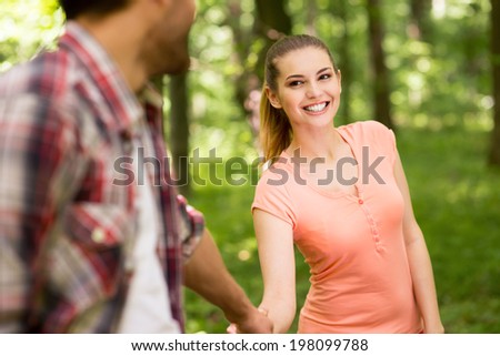Follow me! Playful young loving couple walking in park and holding hands