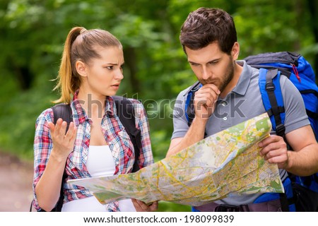 I think we have lost. Thoughtful young man with backpack examining map while angry woman standing near him and gesturing