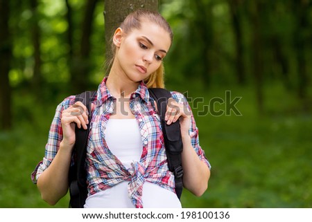 Tired traveler. Side view of tired young man with backpack leaning at the tree and keeping eyes closed