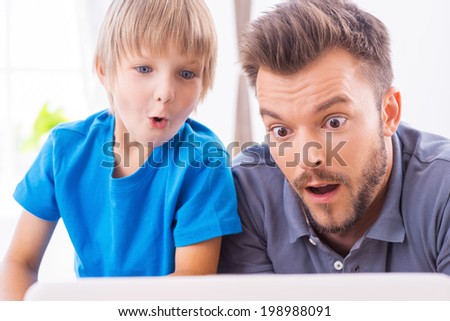 That is unbelievable! Surprised father and son looking at the laptop and keeping mouth open