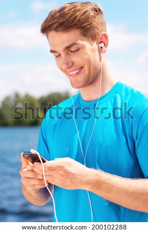 Sporty man. Handsome young man in sports wear standing outdoors and smiling