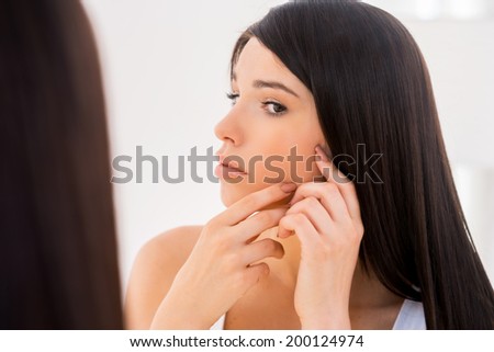 My face should be perfect. Attractive young woman examining her face while looking at the mirror