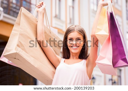 The best therapy is shopping. Attractive young woman holding shopping bags and smiling while standing outdoors