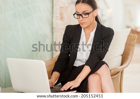 Confident and successful business lady. Confident young woman in formalwear working on laptop while sitting at the comfortable chair