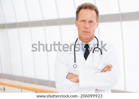 I take my job seriously. Confident mature doctor in white uniform looking at camera and keeping arms crossed