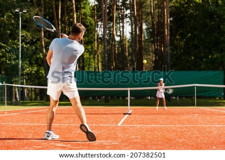 Match point. Full length of man and woman playing tennis on tennis court
