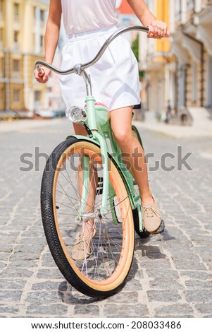 Exploring town by bike. Close-up of young woman riding bicycle along the street
