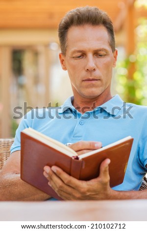 Making some urgent notes. Confident mature man writing something in his note pad while sitting outdoors with house in the background