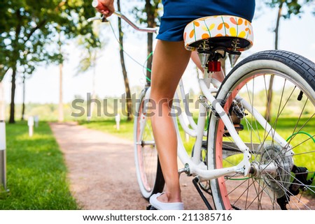 Riding bicycle in park. Close-up of young woman riding bicycle in park