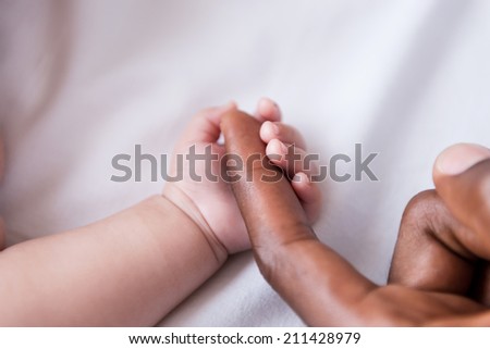 Tiny hand. Close-up of little baby holding fathers finger