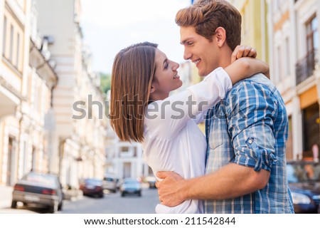 Love is in the air. Beautiful young loving couple hugging and looking at each other while standing outdoors