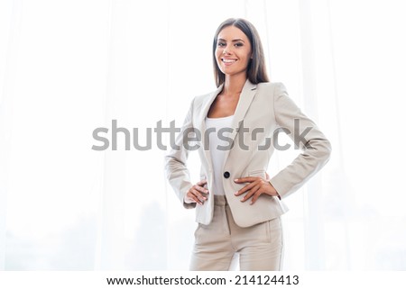 Confident businesswoman. Confident young businesswoman in suit holding hands on hip and smiling