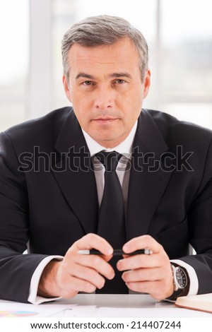 Confident business expert. Confident mature man in formalwear looking at camera while sitting at his working place