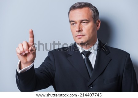 Confident business expert. Confident mature man in formalwear looking at camera and keeping arms crossed while standing against grey background