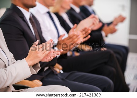Great success. Group of business people clapping hand while sitting in a row