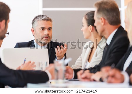 Business meeting. Business people in formalwear discussing something while sitting together at the table