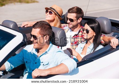 Fun travel. Top view of young happy people enjoying road trip in their white convertible