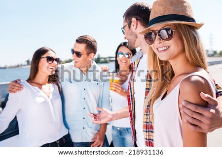 I love my friends! Group of young happy people talking to each other while beautiful woman looking at camera and smiling
